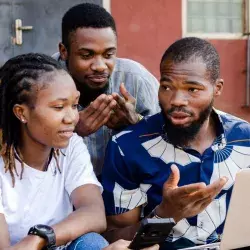2 jóvenes y 1 chica africana, observando una laptop.