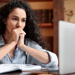 Mujer frente a laptop, con manos en la boca, signo de preocupación