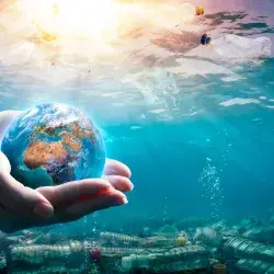 Image of the ocean contaminated with the world held in between two hands