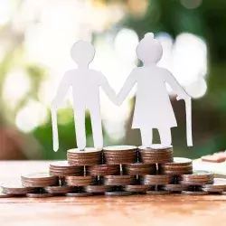 Foto conceptual de una pareja de personas de la tercera edad, sobre monedas, conceptualizando su pensión para el retiro