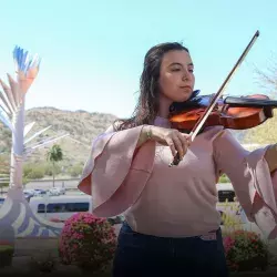 Mariana Páez tocando la viola frente a una vista de la Cápsula del Tiempo del campus Sonora Norte