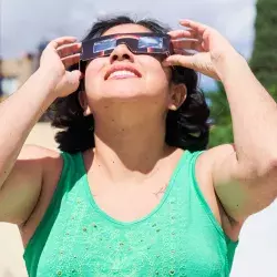 Mujer observa eclipse solar con lentes especiales.