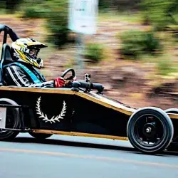 Alumna de Ingeniería del Tec de Monterrey conduce vehículo sin motor color negro con oro en una colina de Arteaga, Coahuila