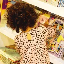 Una niña de cabello chino observa los libros en un stand de la Feria Internacional del Libro de Monterrey 2023. 