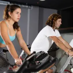Gente en gimnasio en bicicletas estáticas