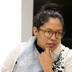 Profesora con lentes, ropa blanca y el cabello sujetado