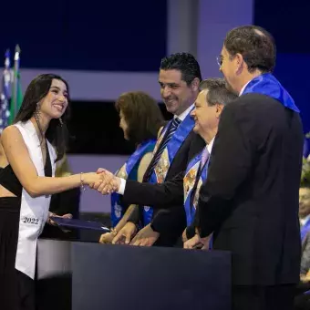 La alumna Andrea Guzmán saludando a miembros del presidium