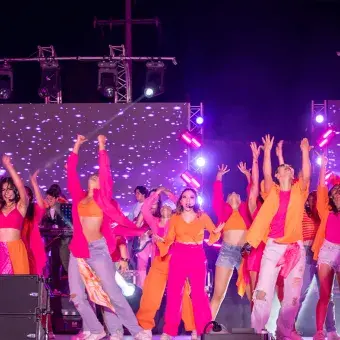 Alumnos cantando y bailando en musical.